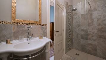 A bathroom with a large sink, a mirror, and a shower area.