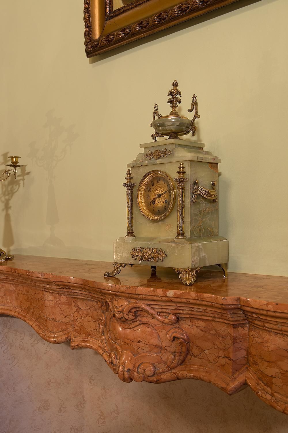 A marble clock with intricate carvings on a mantelpiece.