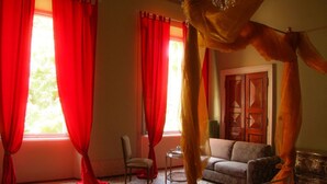 A room with a canopy bed, red curtains, a sofa, and a wooden door. - Salotto delle Arti (Modena)