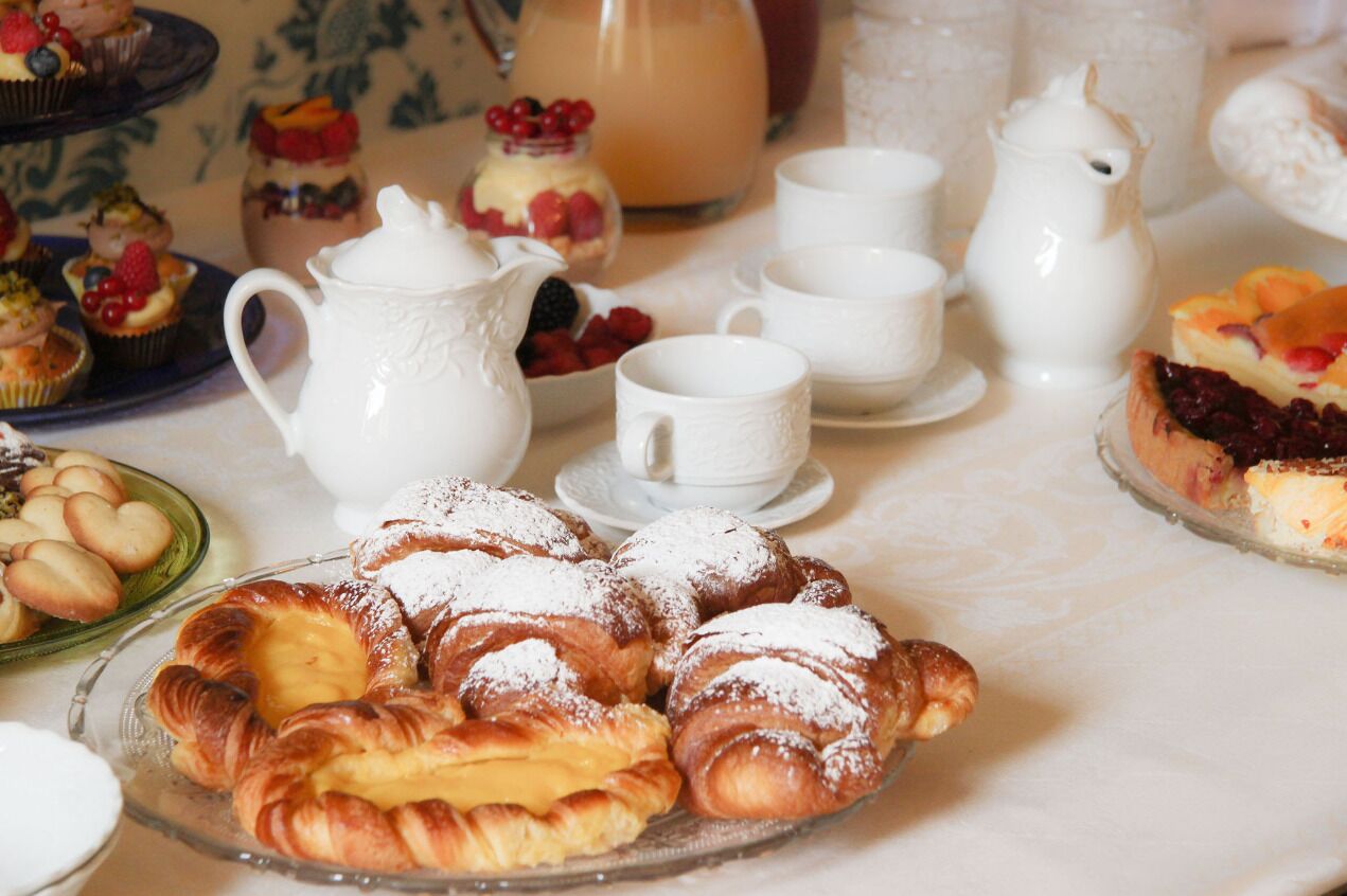 A table with pastries, a pitcher, cups, and a teapot, suggesting a tea service setting.