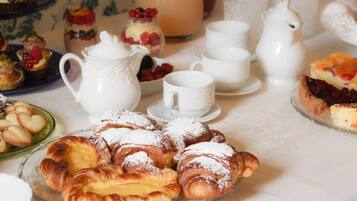 A table with pastries, a pitcher, cups, and a teapot, suggesting a tea service setting.