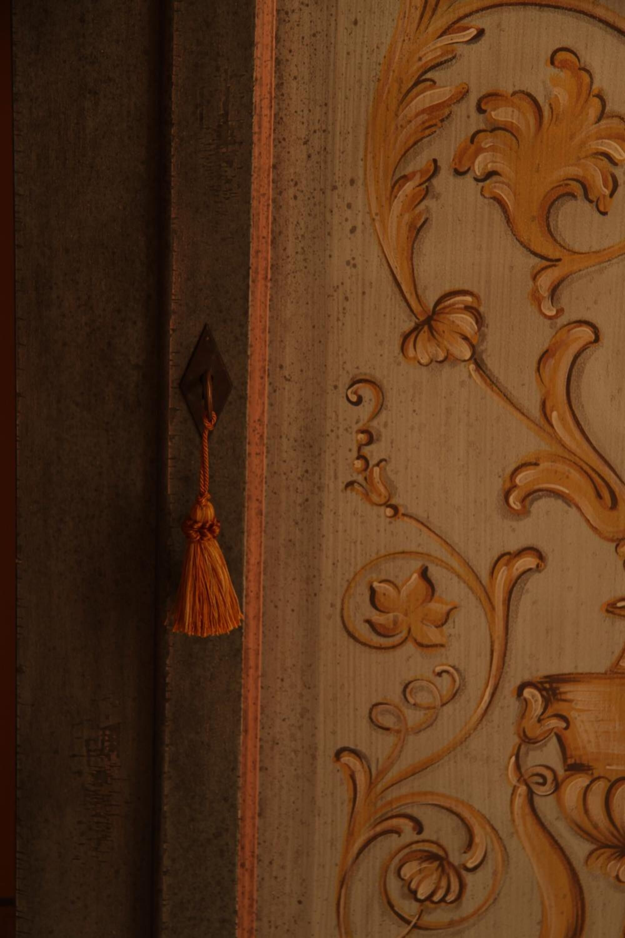 A wooden panel with intricate carvings and a tassel hanging from a hook.