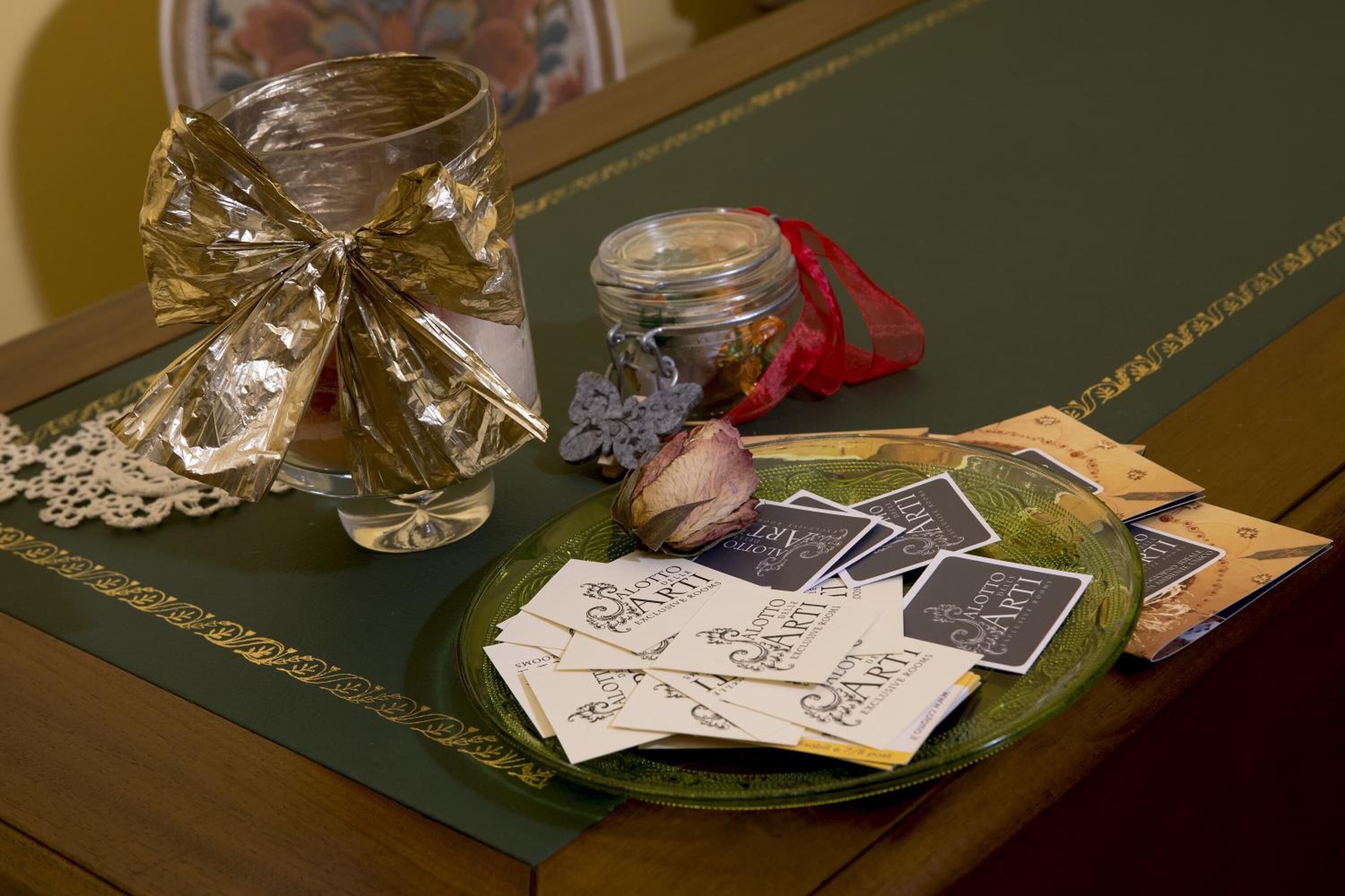 A table with a green placemat, a glass jar with a red ribbon, a decorative bow, and several business cards.