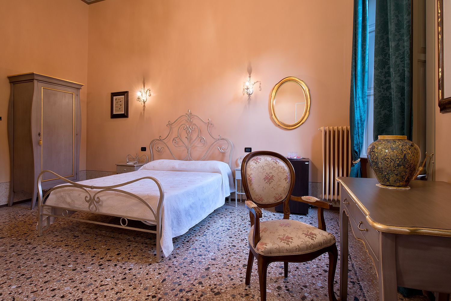 A bedroom with a metal bed frame, a wooden chair, a dresser, a mirror, and a radiator.