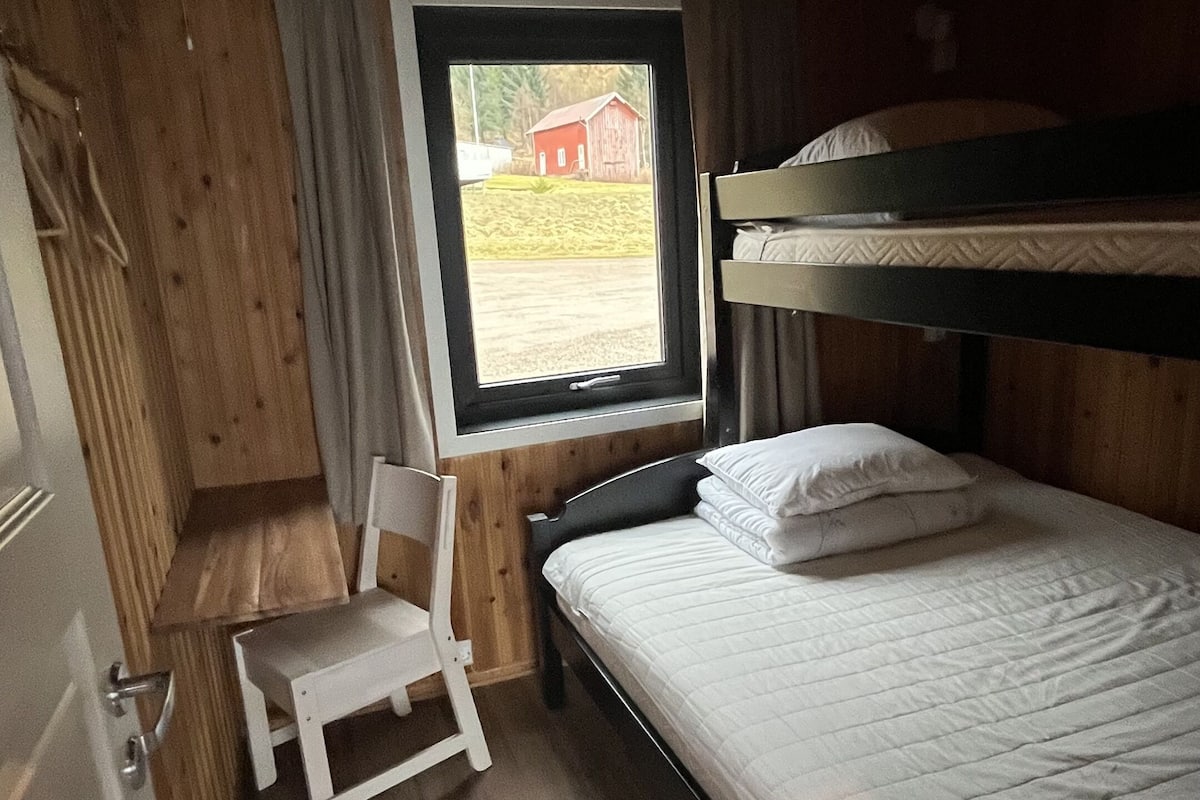 Une cabine équipée d’un lit superposé, d’un petit bureau et d’une chaise.