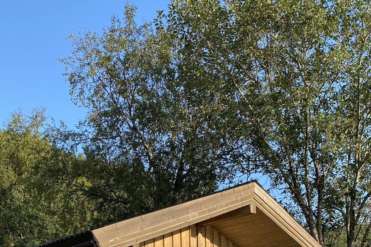 Une cabane en bois dotée d’un balcon, de grandes fenêtres et offrant une vue sur le paysage environnant.