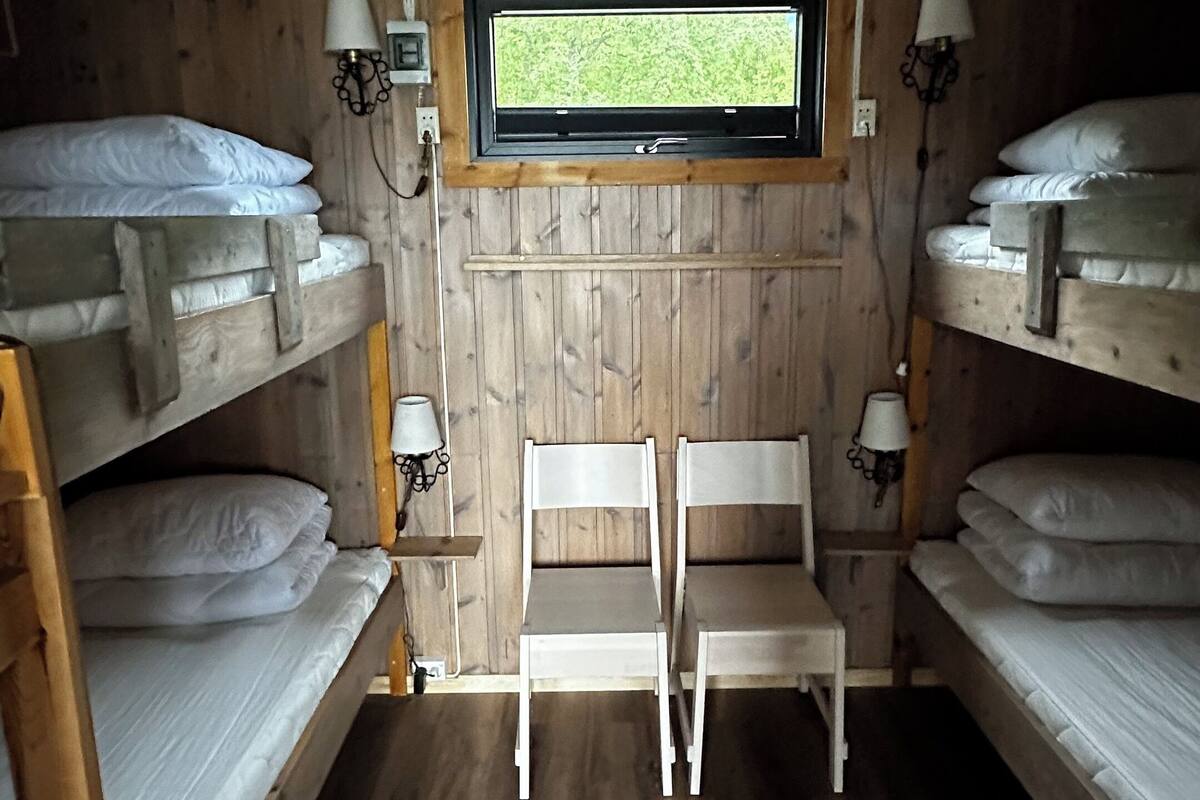 Une chambre de dortoir avec des lits superposés, une petite fenêtre et deux chaises.