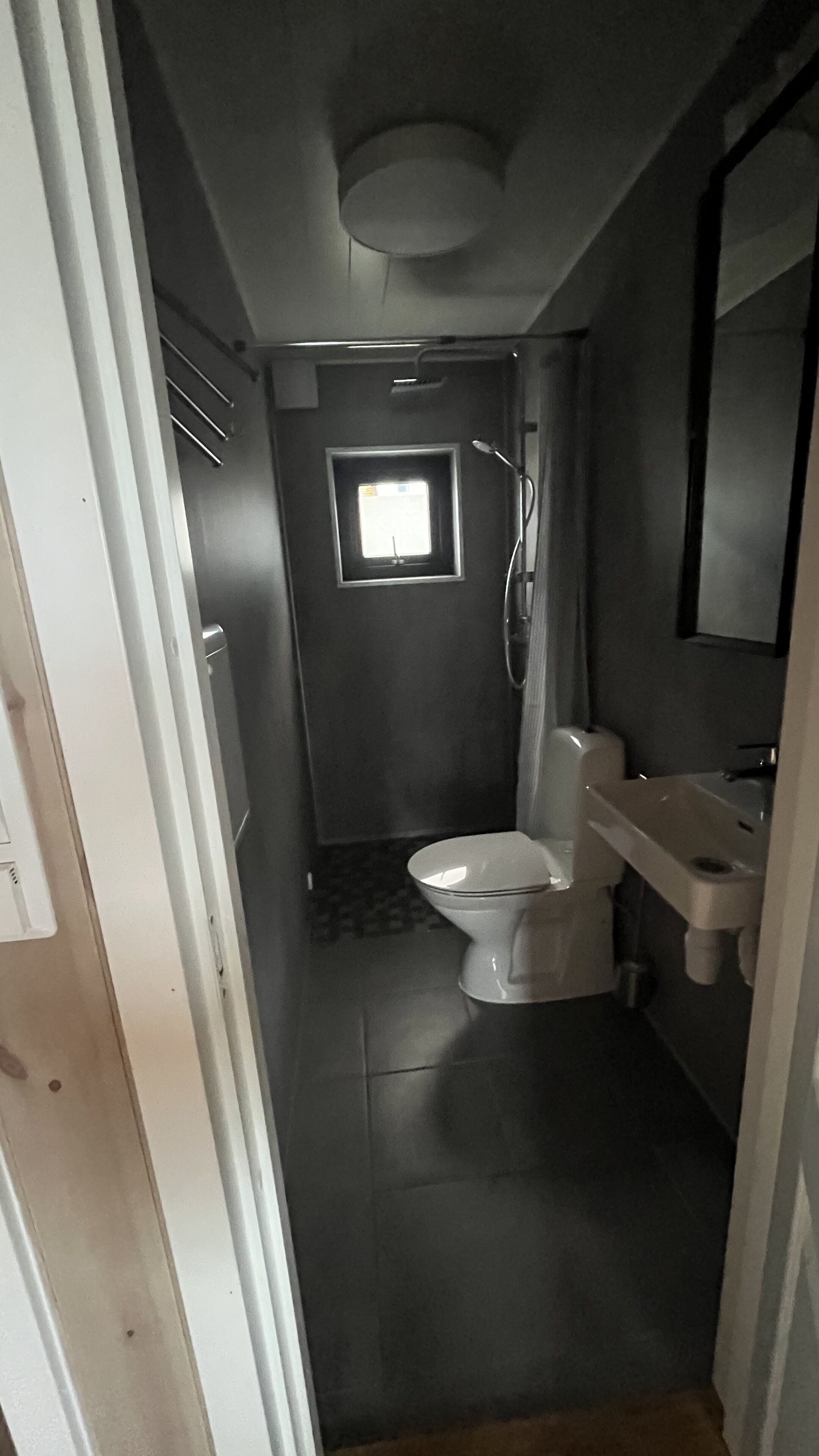 Un baño pequeño con inodoro, lavamanos y ducha.