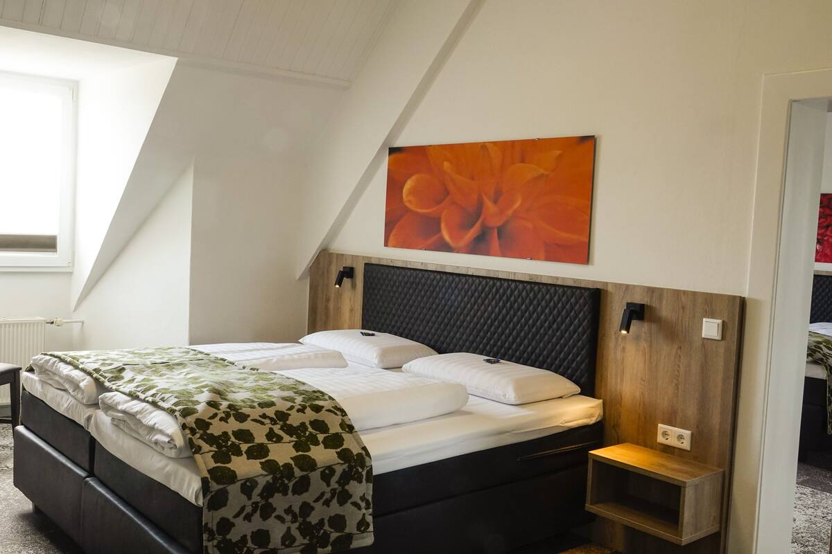 Ein Schlafzimmer mit einem Bett, einem Sessel, einem Heizkörper, einer Wandleuchte und einem Gemälde.