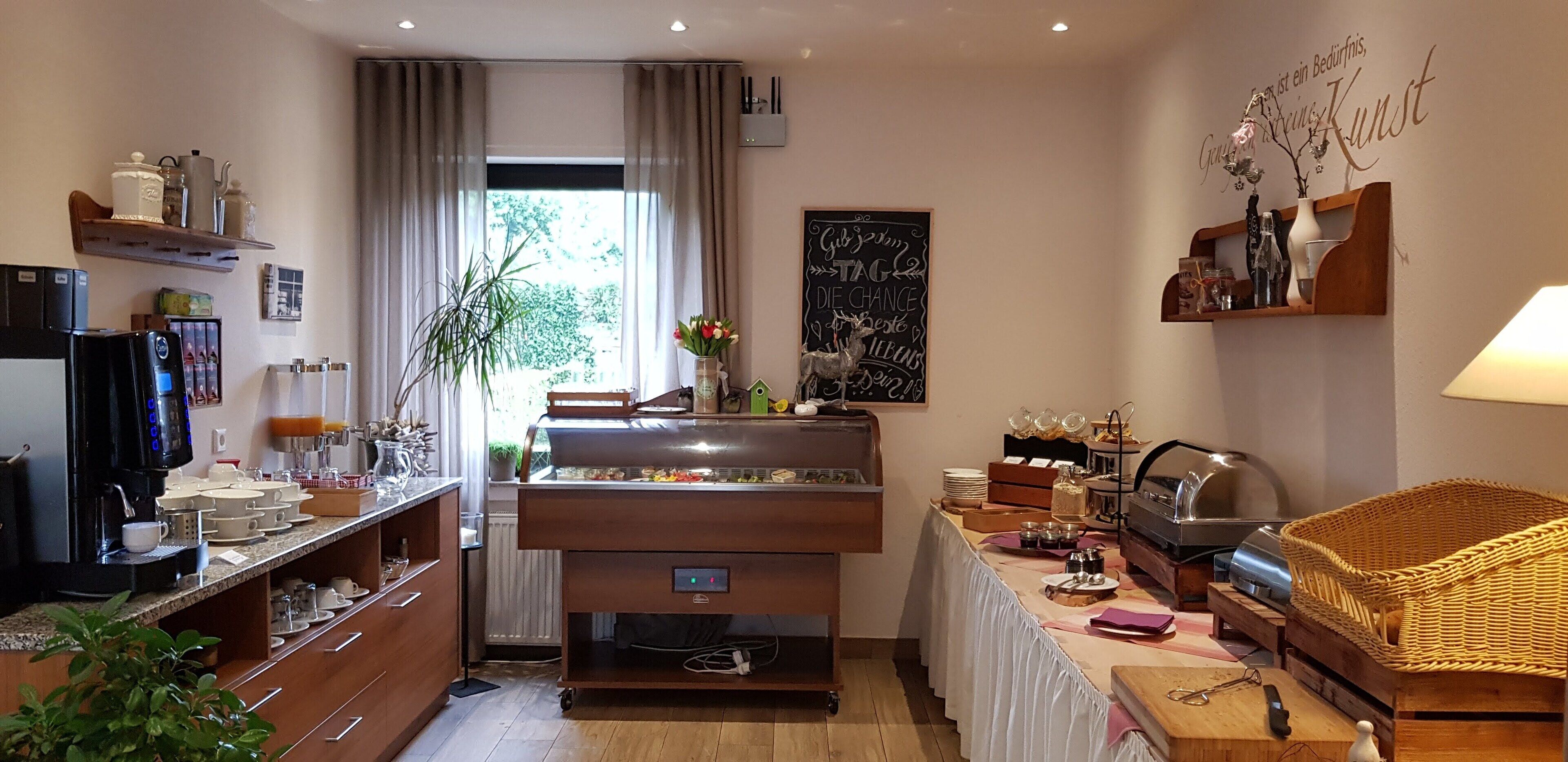 A well-lit kitchen with a coffee machine, a refrigerator, and a dining area with a table set for two.