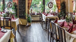 A restaurant with multiple tables set for dining, featuring a wooden floor and natural light from large windows. - Hotel Nierswalder Landhaus (Goch)
