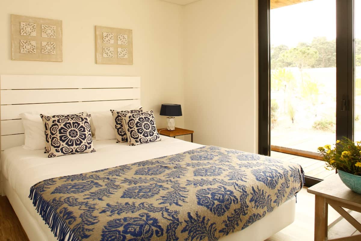 Un dormitorio con una cama grande, dos mesitas de noche, un ventanal con vistas y decoración en la pared.
