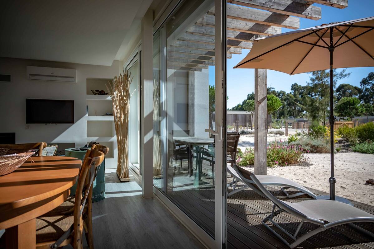 Un interior moderno con zona de comedor, televisor y vistas al patio exterior.