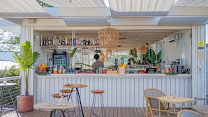 An outdoor bar area with a counter, stools, and hanging lights. - Pestana Tróia (Grandola)