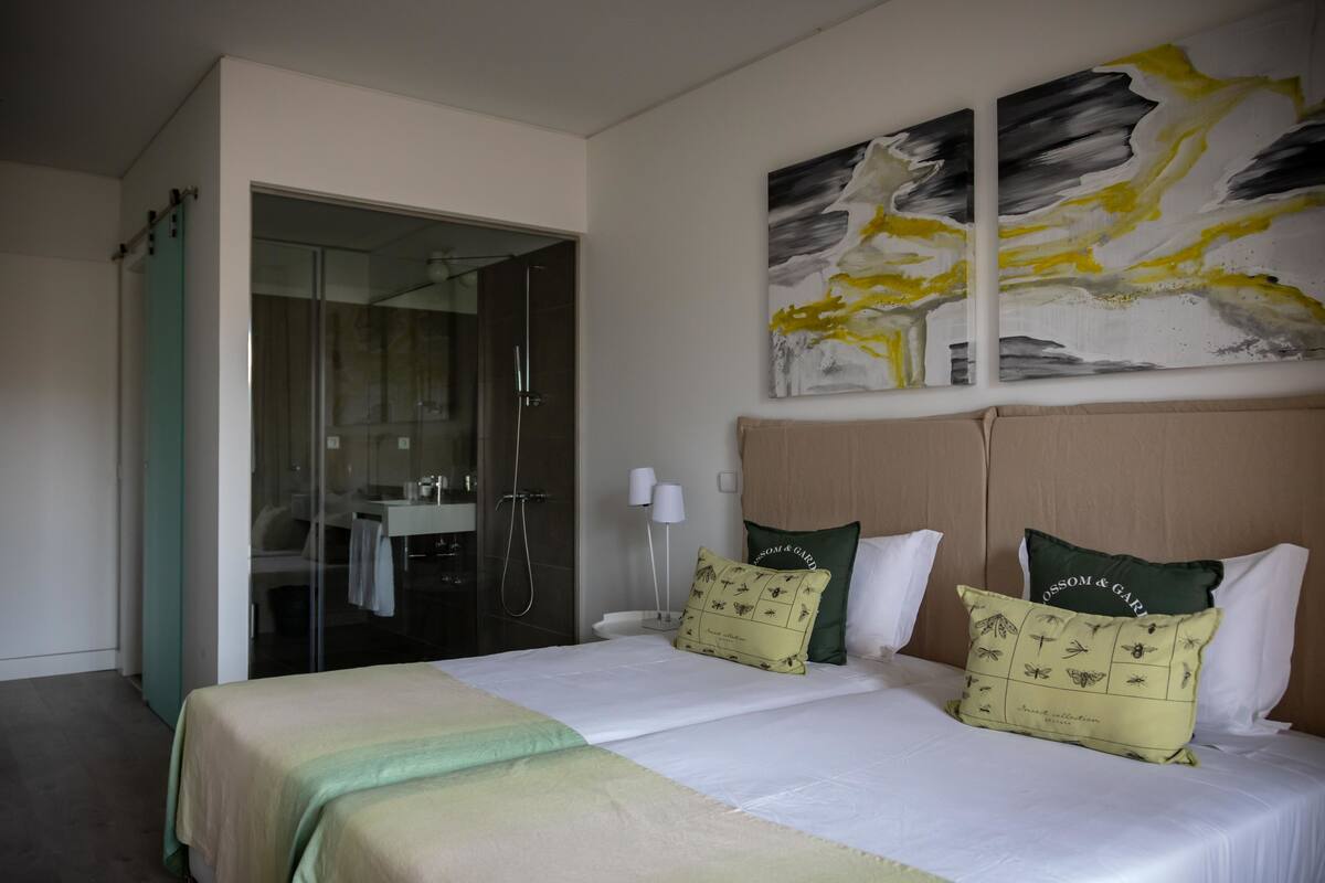 Una habitación de hotel con una cama, ducha y un cuadro en la pared.