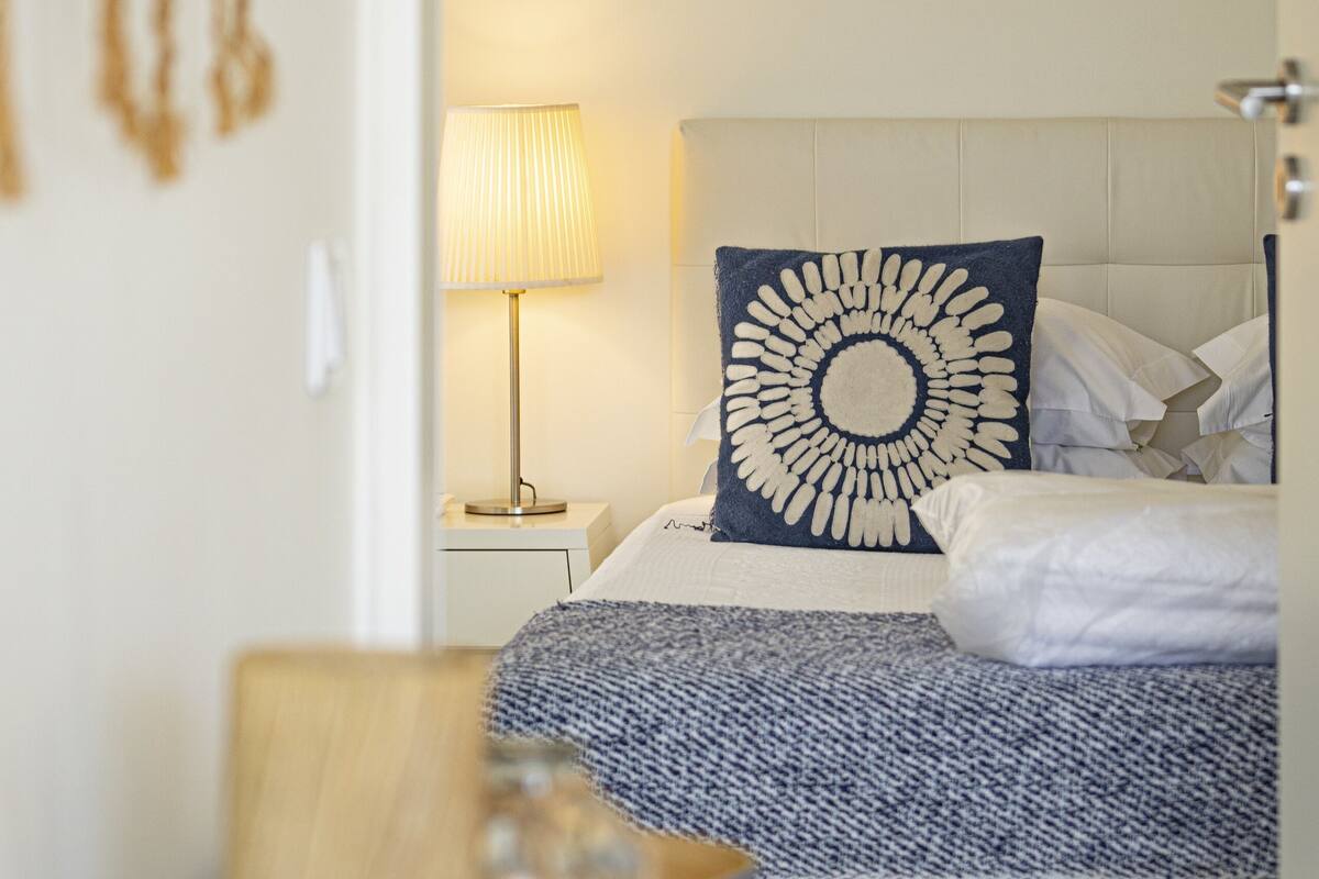 Un dormitorio con cama, lámpara de noche, un adorno en la pared y una mesita de noche.