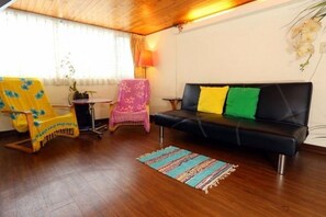 A cozy room with a black sofa, a yellow armchair, and a pink chair. - Jiufen Jiudaokou B&B (New Taipei City)