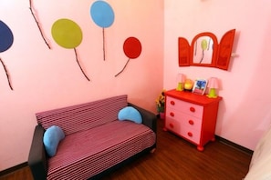 Una habitación con un sofá a rayas, un aparador rojo con cajones y un espejo en la pared.