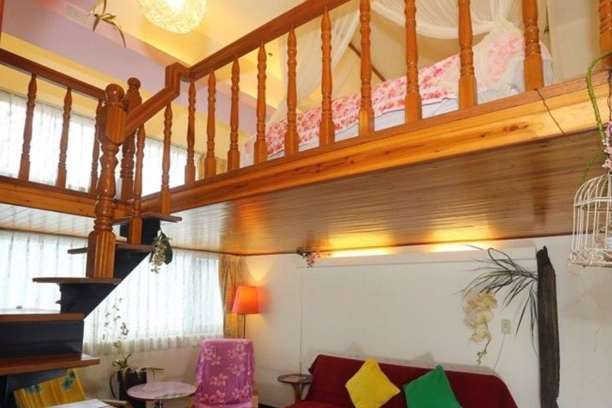 A spacious living area with a red sofa, wooden staircase, and a small round table.
