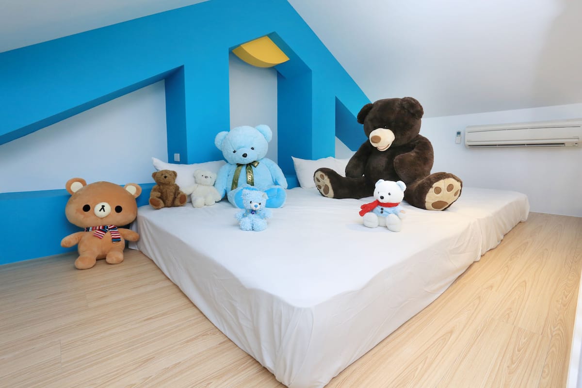 A bedroom with a white bed, blue walls, and an air conditioning unit.