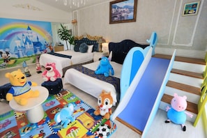 A children's playroom with a slide, plush toys, and a colorful play mat.