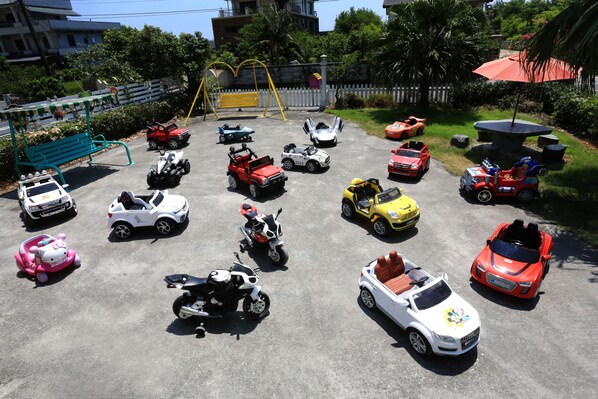 Un parking avec différents véhicules jouets et une balançoire.