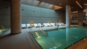 A modern indoor pool area with lounge chairs and a clear pool. - NYX Herzliya (Herzliya)