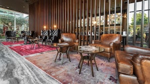 A modern lounge area with leather sofas, round tables, and a red carpet. - NYX Herzliya (Herzliya)