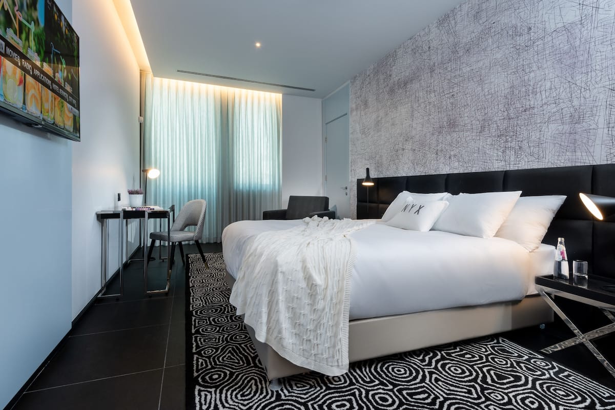 Ein modernes Hotelzimmer mit einem großen Bett, einem Schreibtisch und einem Sessel.