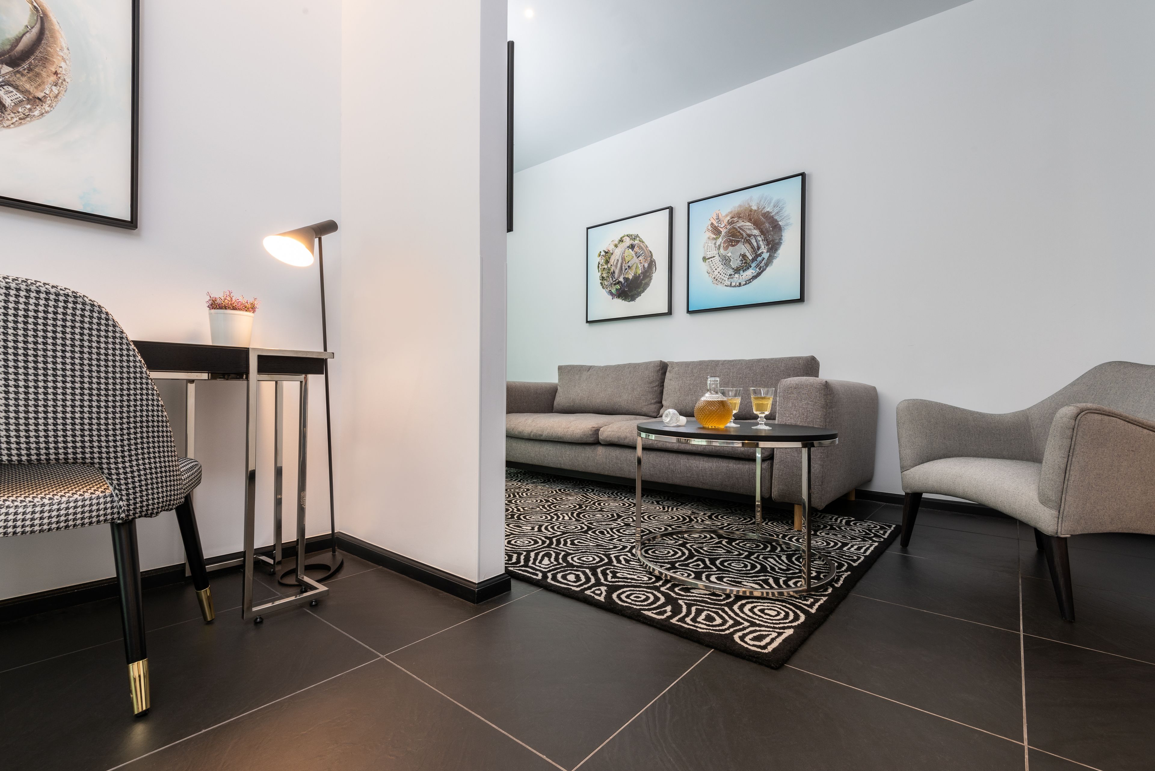 Una sala moderna con un sofá, dos sillones, una mesa de centro, un tapete estampado y una lámpara de pie.