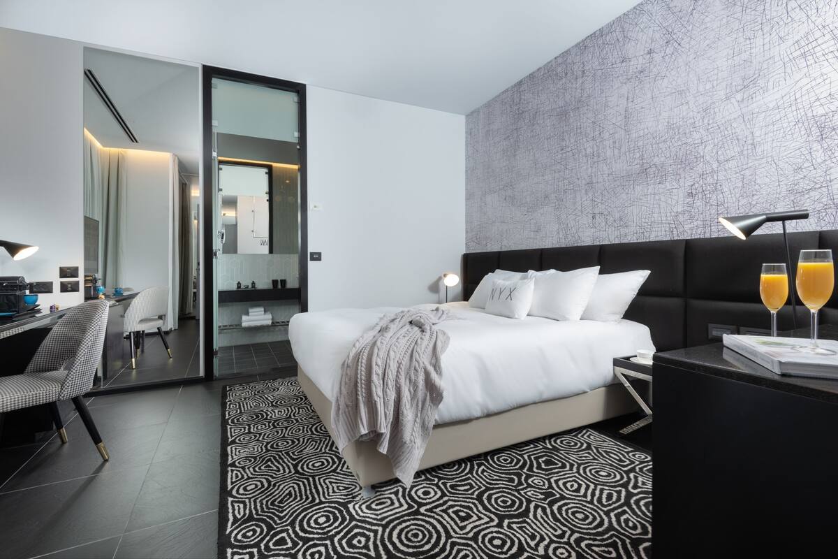 Ein modernes Hotelzimmer mit Bett, Nachttisch und Schreibtisch mit Stuhl.