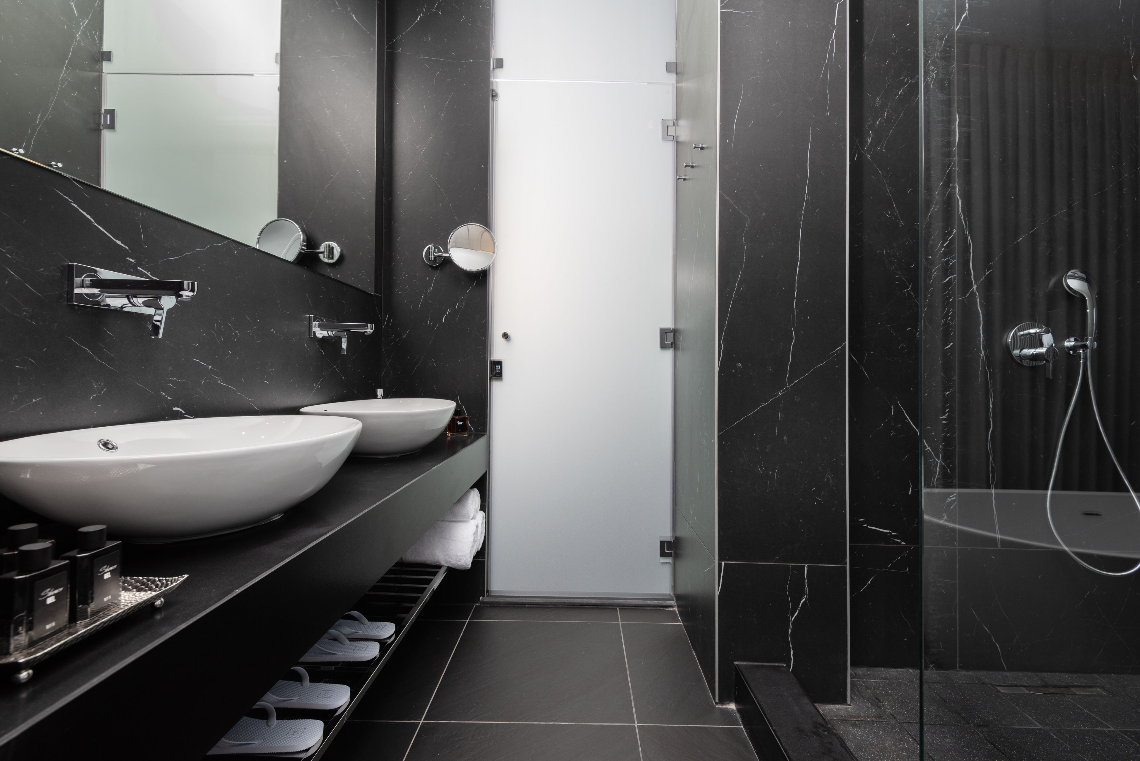 A modern bathroom with two large sinks, a shower area, and a glass-enclosed shower stall.
