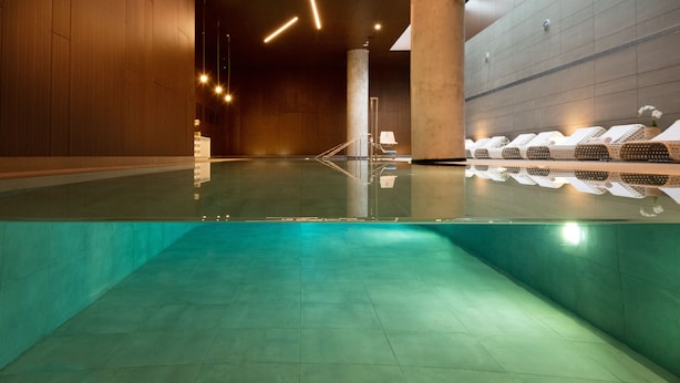 A modern indoor swimming pool with clear water, wooden walls, and a clean, minimalist design. - NYX Herzliya (Herzliya)