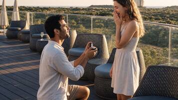 Un hombre le pide matrimonio a una mujer en una terraza en la azotea, con asientos al aire libre y vistas del paisaje.