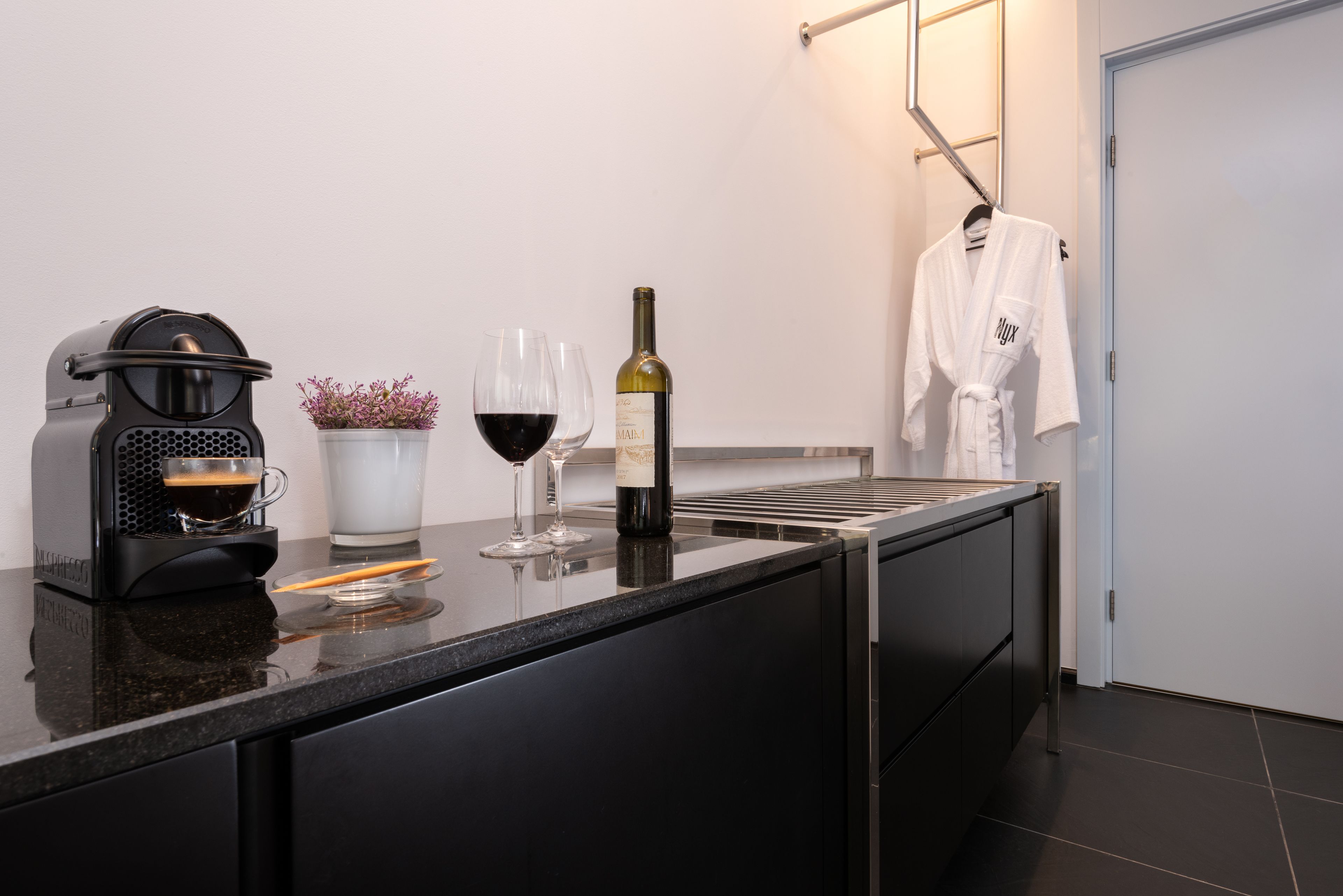 Cocina moderna con cafetera, copas de vino y una botella de vino sobre la encimera.