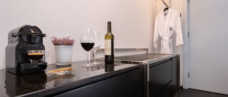 Cocina moderna con cafetera, copas de vino y una botella de vino sobre la encimera.