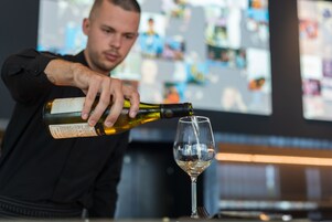 Una persona sirviendo vino en una copa.