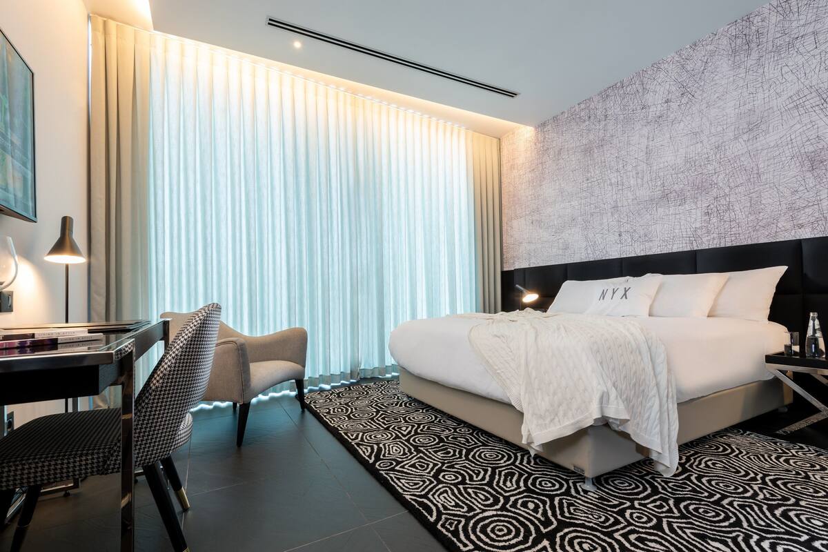 Ein modernes Hotelzimmer mit einem großen Bett, einem Schreibtisch und einem Stuhl.