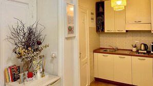 A kitchen with white cabinets, a wooden countertop, a sink, and a hanging light fixture. - Domus Romana B & B (Rome)