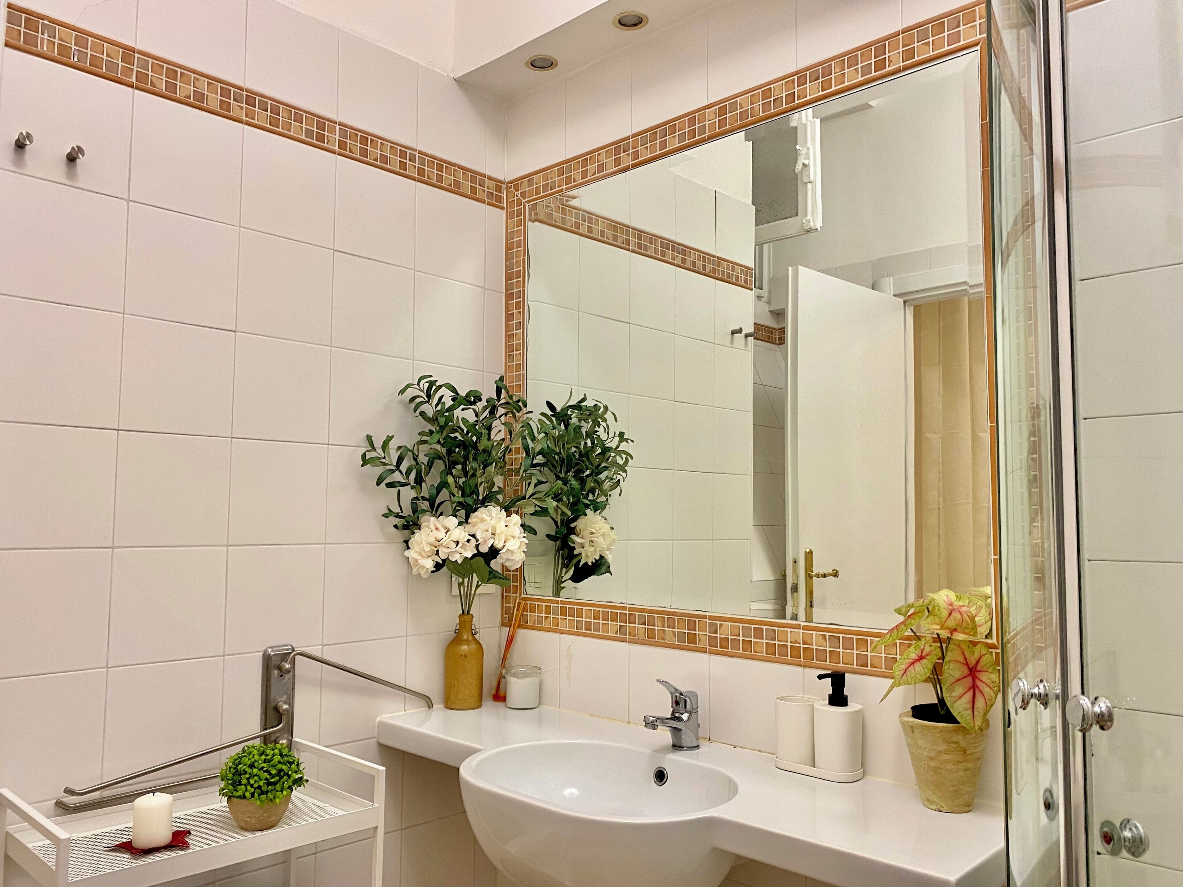 A bathroom with a white sink, a large mirror, and a glass shower door.
