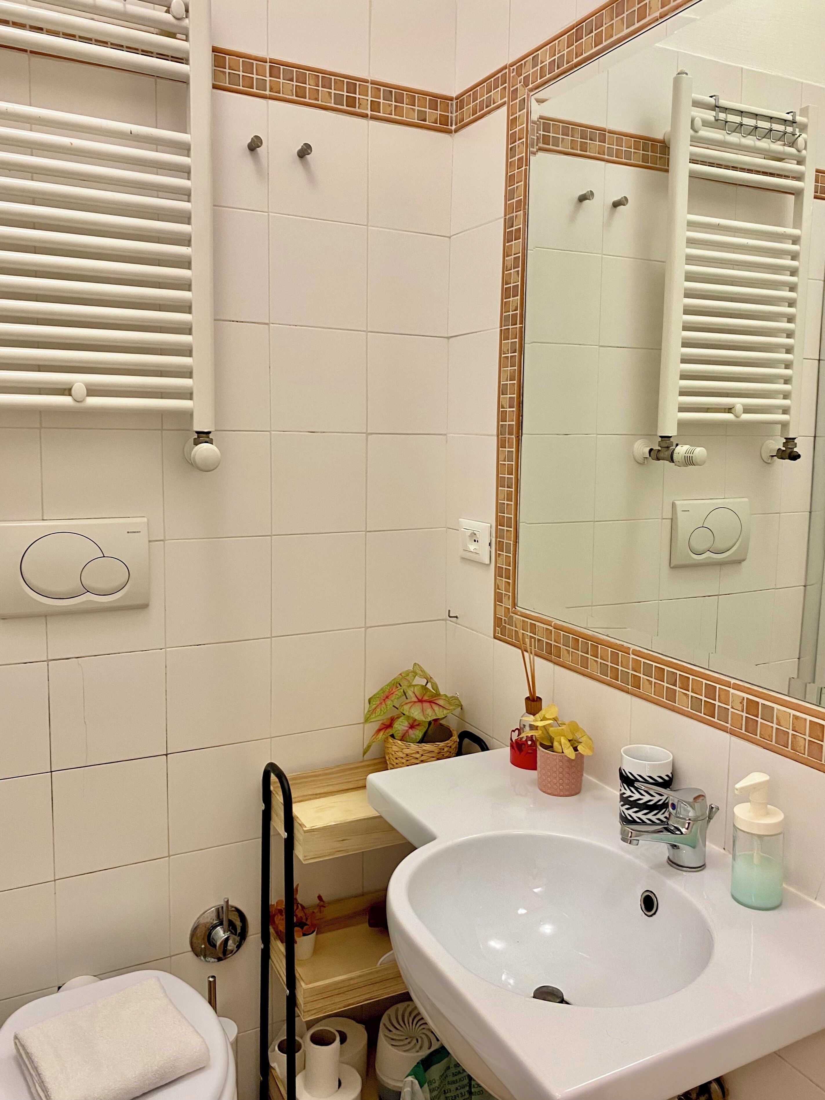 A bathroom with a white sink, mirror, towel rack, and toilet.