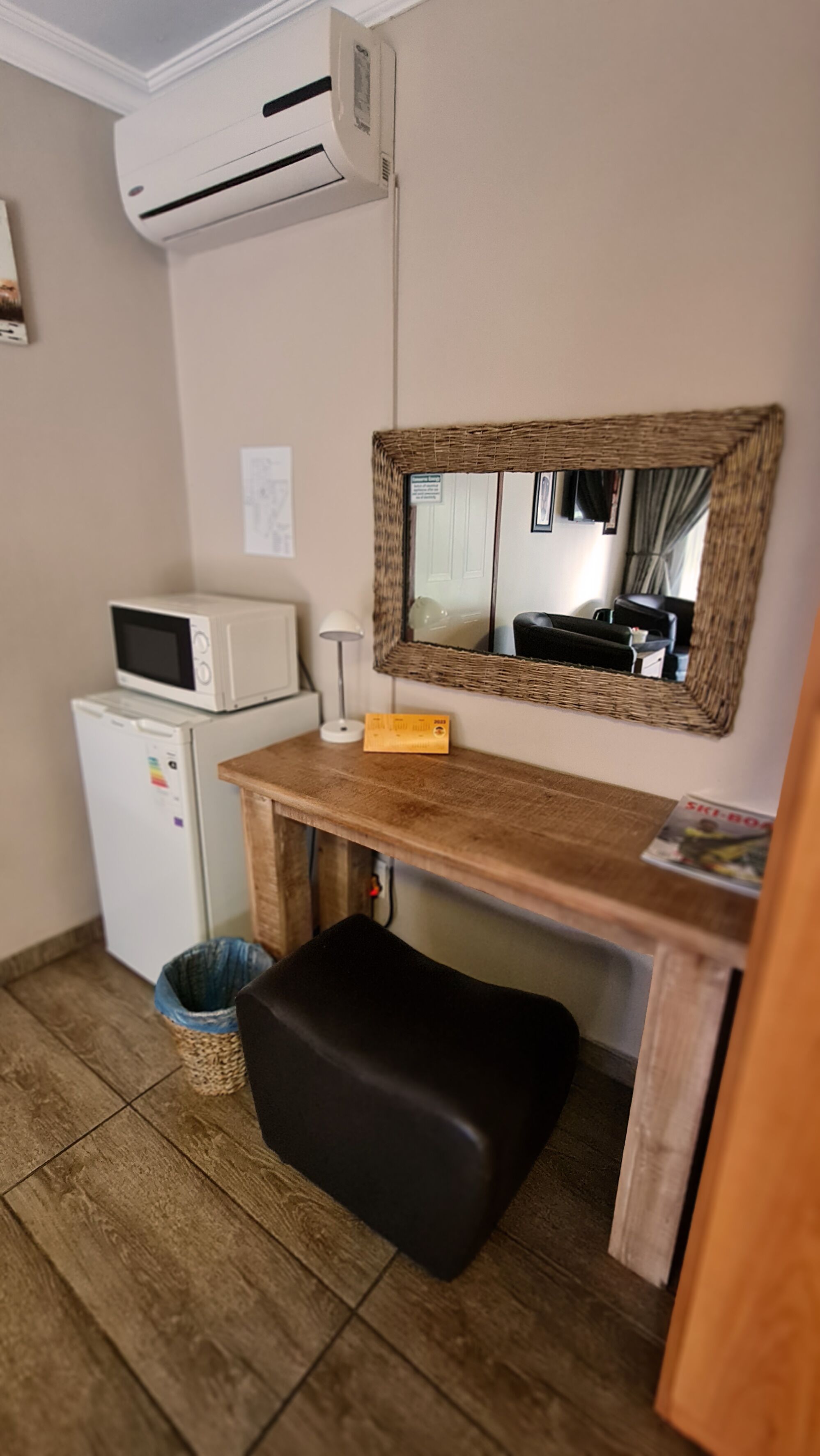 A compact kitchenette with a microwave, refrigerator, and a small trash bin.