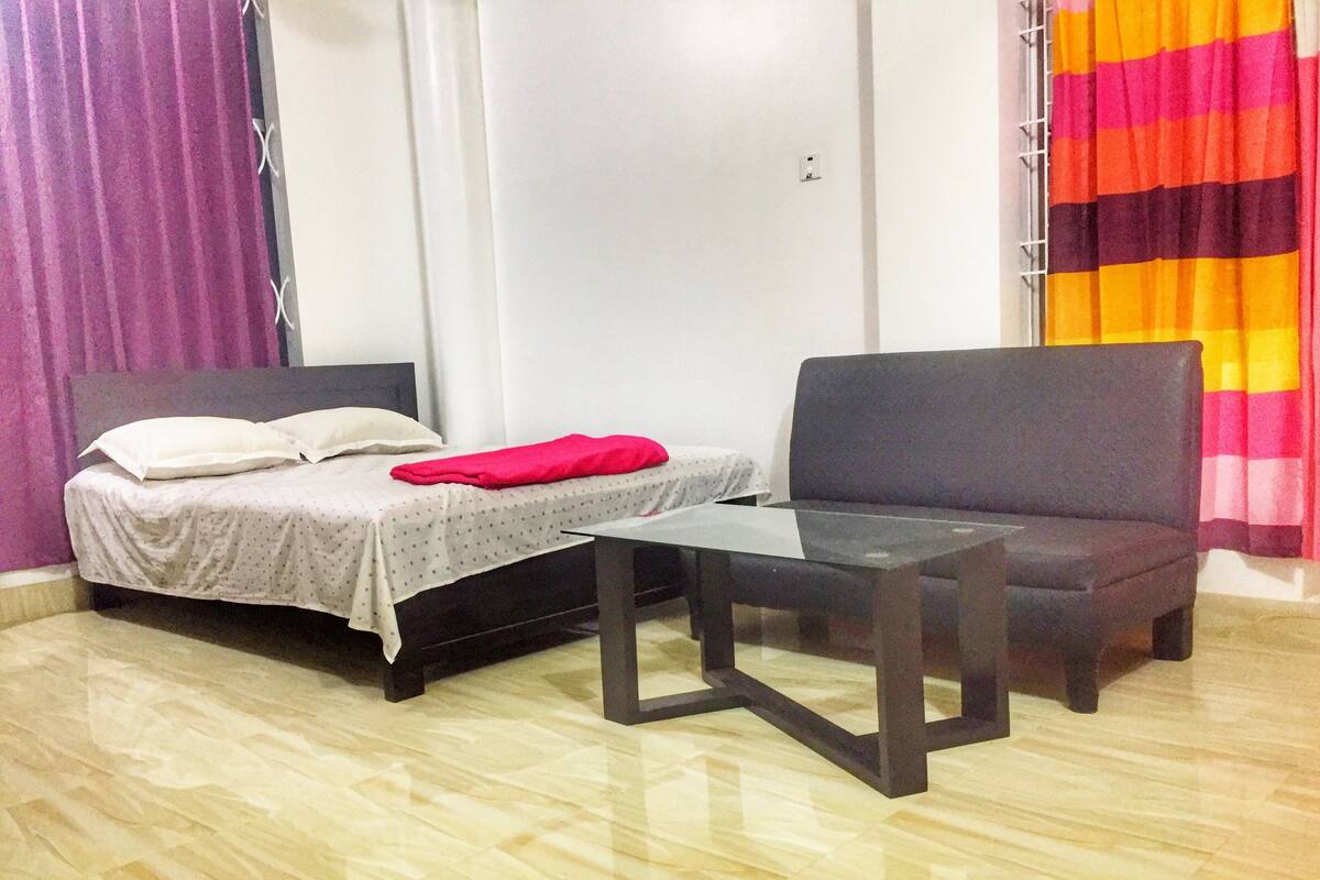 Une petite pièce, bien rangée, avec un lit, une chaise et une table.