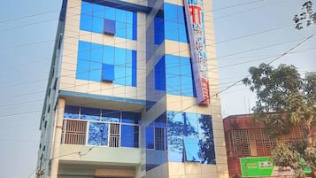 A multi-story building with a modern facade, featuring large windows and a prominent vertical sign.
