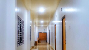 A long, narrow hallway with a shiny marble floor, white walls, and doors on both sides.