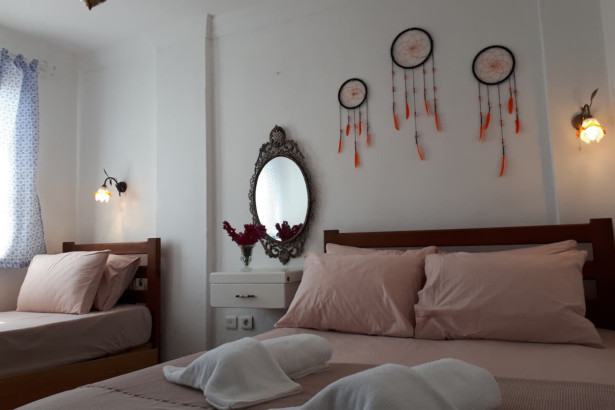 Un dormitorio con una cama, dos mesitas de noche, un espejo y atrapasueños colgados en la pared.