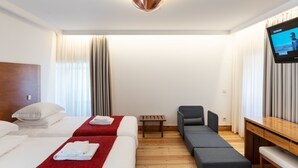 Een hotelkamer met twee bedden, een televisie, een tafeltje en een bank.