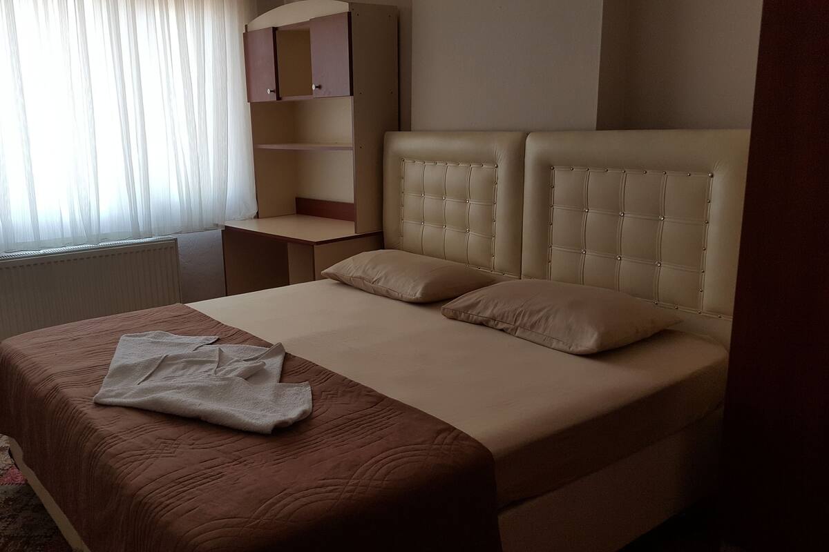 A bedroom with a bed, a bedside table, a wardrobe, and a radiator.