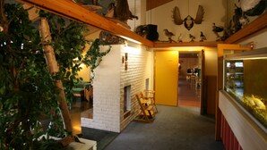 A room with a brick fireplace, wooden beams, and a variety of mounted animal heads on the walls. - Overhalla Hotel (Overhalla)