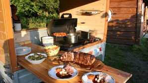 An outdoor barbecue setup with a grill, pots, and a variety of dishes including meat and vegetables. - Overhalla Hotel (Overhalla)